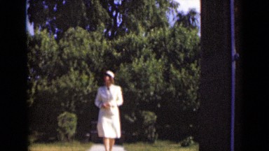 1947: Woman in White Dress Walking Through Garden in New York