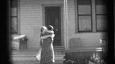 1937: two friends hugging in front of white painted house. BEND OREGON