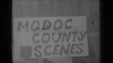 1937: someone writing "modoc county scenes" on white sign in black letters