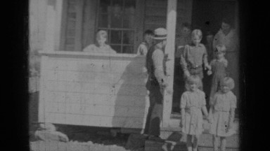 1937: children file out of wooden building passing man and followed by woman