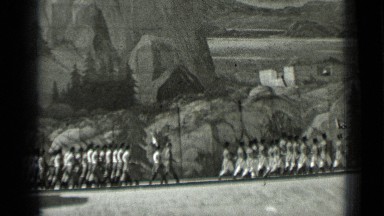 1937: marching soldiers with rifles on their shoulders approach civilians