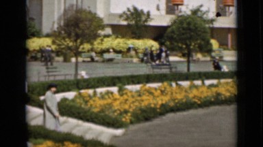1937: woman walking to outdoor water fountain with guardian garden statues