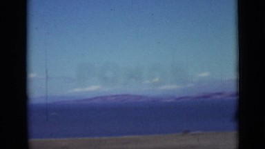 1937: lots of car is parked at shore and mountain, sea at background