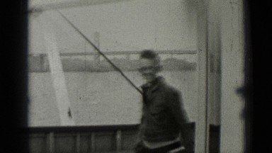 1937: adolescent boy rounds corner of boat while smiling and carrying book
