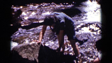 1938: during vacation,person crossing water carefully with help of another