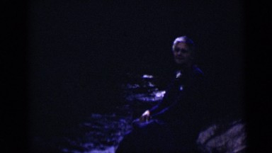 1938: an old woman in dark sitting at corner of river COLORADO