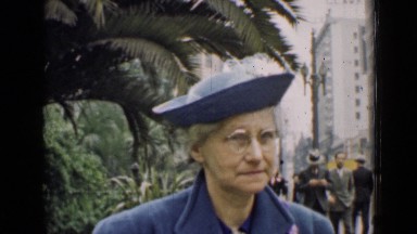 1939: an old women smiling at camera and people's walking alongside ARIZONA