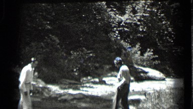 1939: two men are helping together while crossing rocks between water CLEAR LAKE