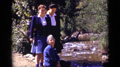 1939: there is water two girls are sitting, one girl is standing COLORADO