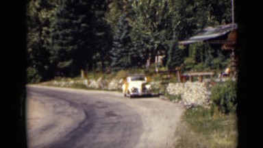 1939: car is parked at side of country road by house with german shepherd