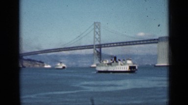 1939: large passenger ship cruising through harbor with beautiful bridge