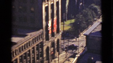 1940: Gardener Sprinkling Water on Roadside Garden as People Enter Office