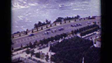 1940: long road next to ocean and lot of cars driving by and people walking.