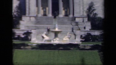 1941: Running Water Fountain with Female Statues in Front of Building