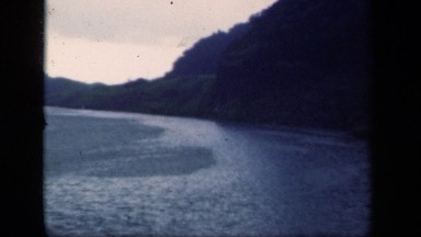1941: beautiful ocean streaming by mountains and hills under nice grey sky.