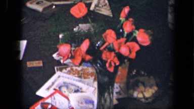 1942: red flowers in vase on table with valentine candy hearts and cards SEBRING