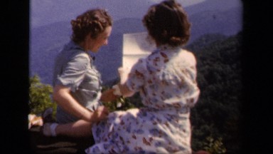 1943: two women looking at map while sitting on hill and sightseeing SKYLINE