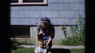 1958: mother poses with child and dog walks by MINNESOTA