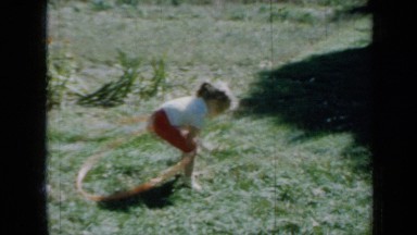 1958: small girl full of energy playing with her exercise ring outside her home
