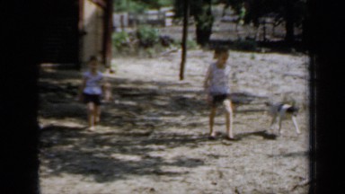 1958: children walk with dog, amusement rides set up, and busy man and women