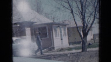 1958: person walking along pathway, talking with somebody where children are