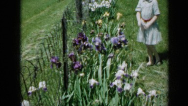 1958: two young girls in light blue dresses smelling flowers