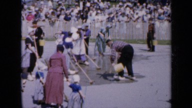 1959: people cleaning road watched by huge crowd IOWA