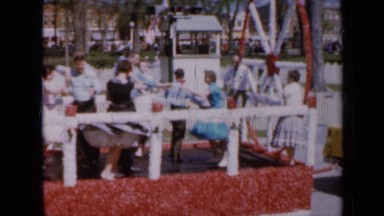 1959: many people dancing on moving float pulled by low vehicle through town
