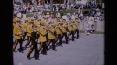 1959: crowd observing parade including band and individuals marching