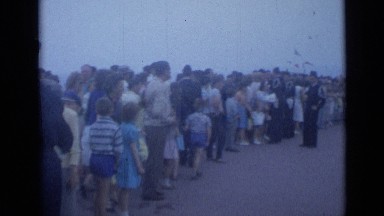 1962: various people standing in long line as man in uniform addresses crowd