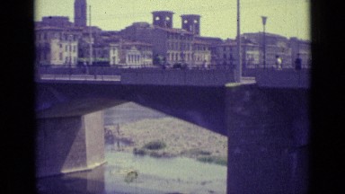 1962: Florence, Italy River Flowing Under Bridge with Cars Alongside
