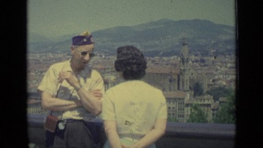 1962: three people engaged in conversation on balcony of building in city