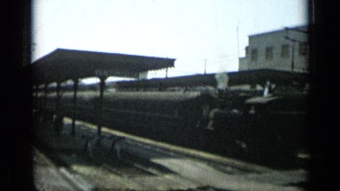 1962: arrival at train station, three men with red traveler's sacks walk away