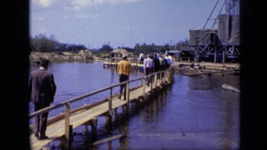 1971: large body of water where people are walking toward industrial site