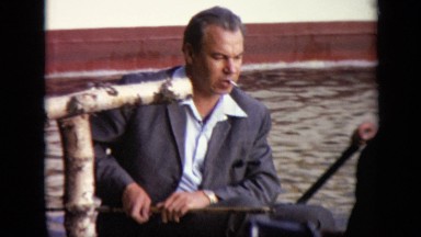 1971: vintage footage of two men in suits riding in small boat being paddled