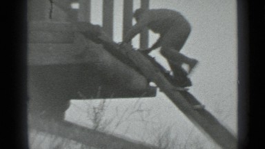 1983: boy climbs down ladder with friend's help in old gray scale film. RUSSIA