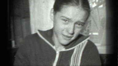 1983: young person sits in front of curtained window and picks side of face
