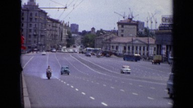 1971: view of road and moving traffic from both lanes with building alongside