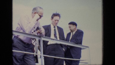 1971: various men in suits, one who appears to be photographer or reporter