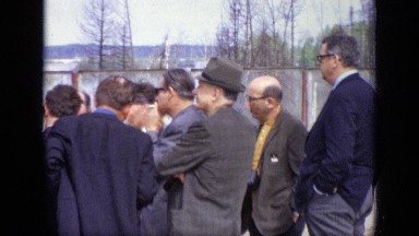 1971: gathering of well dressed men outdoors with one man fixing shirt cuff