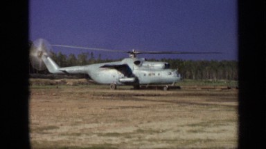 1971: large helicopter against blue sky, kicking up dust storm as it rises