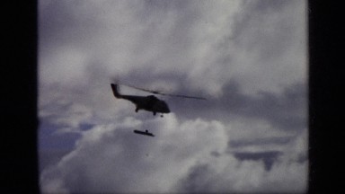 1971: helicopter flies across overcast sky carrying missile. MOSCOW RUSSIA