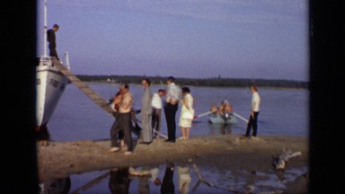 1971: boatmen on bow look down at people standing and walking on sand bar MOSCOW