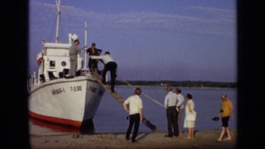 1971: tourists boarding small boat that is anchored on sandy beach. MOSCOW