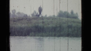 1967: as it rains, four men are standing on shore along river and another man