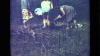 1967: three women working to prepare camp fire by gathering and placing wood