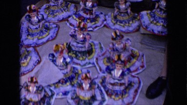 1963: collection of dolls, in traditional garb of elderly woman sitting next to
