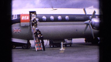 1963: passengers disembark on stairs from jetliner at airport hangar. ENGLAND