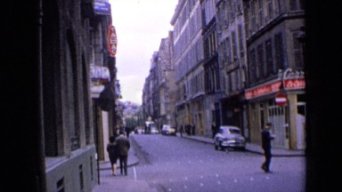 1963: in middle of street, between buildings with some people walking