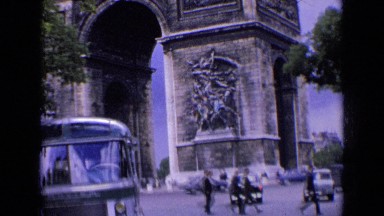 1963: Vehicles and People Moving Under Huge Monument in Town France